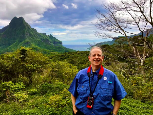 Madison Hall poses for a photo in front of mountains in Polynesia.